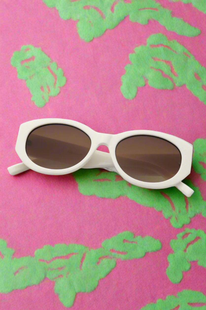 round white girls sunglasses on pink and green beach towel