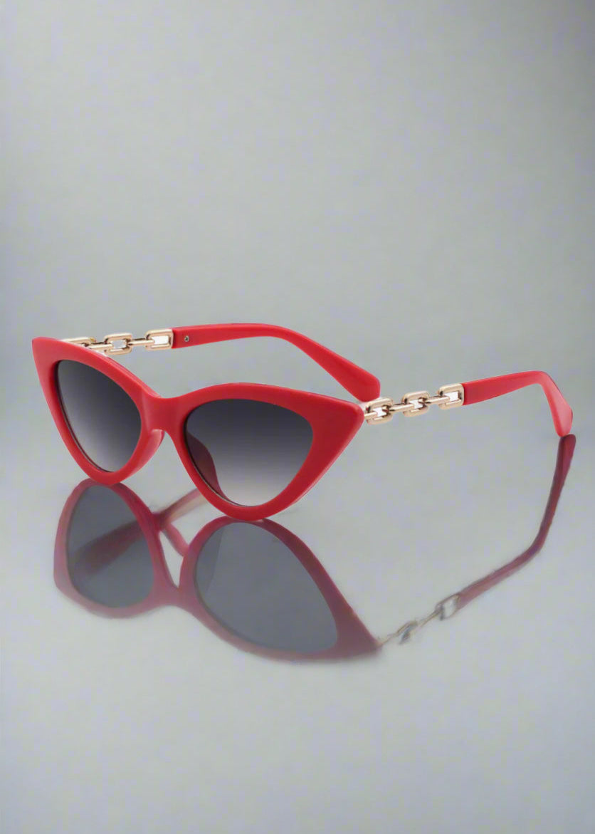 Red Vixen cat-eye sunglasses resting on a stylish mirror , radiating confidence and bold style.